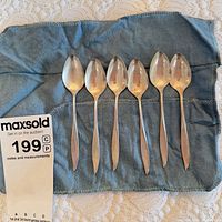 Six sterling silver teaspoons on blue cloth