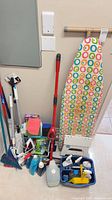 Overall lot showing ironing board, mop, brooms, cleaning caddy, bottles and step stool