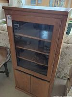 Front view showing glass door, shelves, and lower cupboard