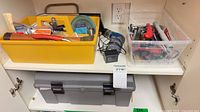 Shelf showing yellow tote of tools, clear bin of tools, gray toolbox