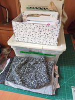 stacked cardboard file organizer filled with paper sewing patterns placed on plastic tote with folded fabrics