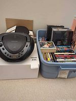 Memorex boombox beside tote filled with DVDs/CDs