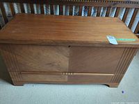 Front view of wood veneer blanket chest showing lock, fluted corners, bracket feet