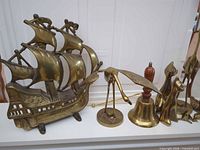 Group view showing brass sailing ship, wood-handled bell, crane, candlestick, robed bells and other figures