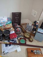 Group shot of entire lot showing book, barometer, figurine, model cars, mugs, cane, plaque, house, flag