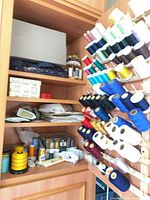 Cabinet interior showing rack full of spools, shelves with sewing supplies