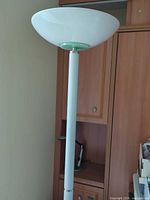 Upper section showing frosted glass torchiere shade and white metal pole