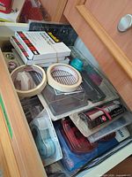 Drawer view showing boxed Scotch adhesives, adhesive rolls, tape runners, circle punch, additional tools