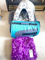 Grouped view of hooded bed, carrier, blanket in front of fireplace