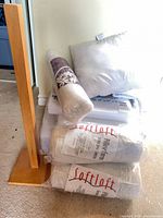 Lot overview showing wooden stand, square pillow, bolster, three packaged inserts