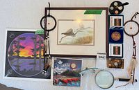 Group shot of all items laid out including framed print, unframed print, dreamcatchers, coins, magnifying glass