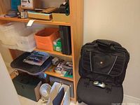 Overall view of shelving with storage bins, office supplies, fan, toolbox, Swissgear bag and Logitech mouse