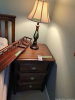 Nightstand with lamp on top and wooden shelf resting across