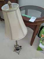 Lamp with shade beside wooden glass-top table