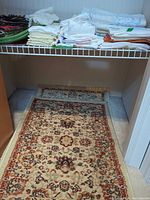 Runner rug on closet floor, beige with red/brown motifs