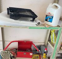 Shelf with paint tray, plastic sheeting, cleaner jug, toolbox, jumper cables, aerosol can
