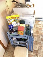 Overall lot showing utility cart, watering can, stool, pet food bag, tins, hardware