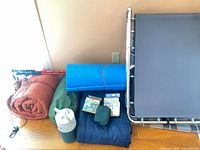 Group shot of all camping items: cot, sleeping bags, foam pad, trekking poles, water jug, accessories