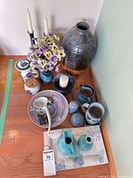 Group shot showing majority of ceramic pieces, large vase, candle holders, faux flowers, fountain bowl, pitchers, tray