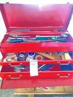 Overview of open red toolbox showing lid, three drawers, assorted tools and accessories inside