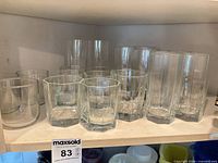 Shelf with mixed clear glass tumblers, both tall and short variants