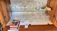 Shelf with assorted stemmed and non-stemmed glassware showing quantity and types