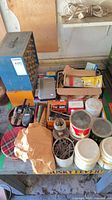 Tabletop view showing jars of nails, radios, boxes of fasteners and scale