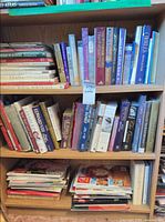 Three shelves packed with books, lower shelf stacked magazines