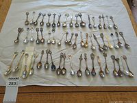 Full layout of approximately 55 souvenir teaspoons on sheet