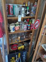 Cabinet with glasses, beer cans, mugs, sign, ashtrays