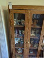 Full view of oak-look glass-door cabinet with contents visible