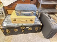 Stacked view of steamer trunk with three suitcases