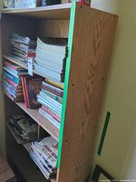 Right side view of tall oak-tone veneer bookcase with magazines on shelves