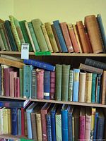 Three shelves filled with cloth-bound hardcover books showing colour variety and quantity