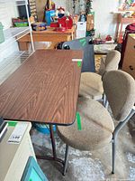 woodgrain laminate folding table with two upholstered folding chairs