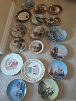 Group view of 18 decorative nautical plates on carpet