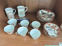 Cabinet shelf with 2 royal mugs, 6 teacups, 12 plates