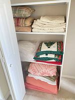 Closet shelves with pillows, folded quilts, blankets and curtain panels