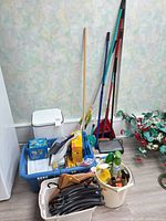 Group shot of all items: basket with hangers and cleaners, waste bin, bucket with cleaners, broom handles, dustpan, vacuum parts