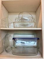 Full view of cabinet shelves showing all stacked glass bakeware pieces
