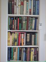 Full frontal view of three shelves densely packed with hardcover and paperback books