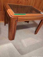Corner view of wooden side table showing leg design and glass inset