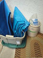 Medalta crock beside Rubbermaid tote containing two blue tarps
