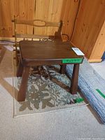 Dark brown wooden footstool viewed from top and side on decorative rug