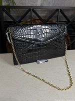 Front view of black faux croc envelope clutch with gold chain strap