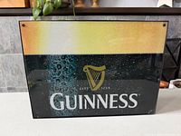 Front view of illuminated Guinness sign showing full artwork and frame