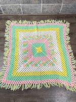 Full view of square granny square baby blanket showing colors and fringe