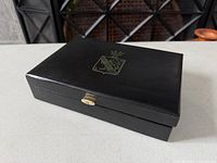 Closed box top view showing gold crest and clasp