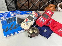 Group shot of all items: two plush cars, two packaged flags, clock, red and navy scarves