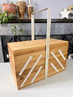 Closed wood cantilever sewing box front and handle visible